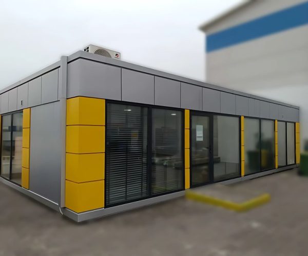 Corner view of a grey modular office building with yellow accent panels and a roof-mounted air conditioning unit