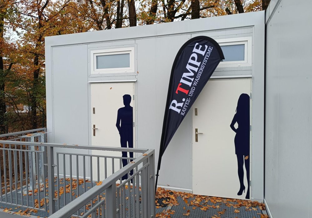 White portable twin toilet unit with separate male and female door graphics and an external access ramp