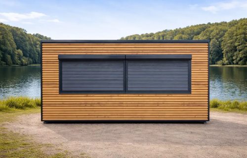 Portable catering kiosk with horizontal timber cladding and twin anthracite roller shutters, front elevation beside a lake with woodland backdrop