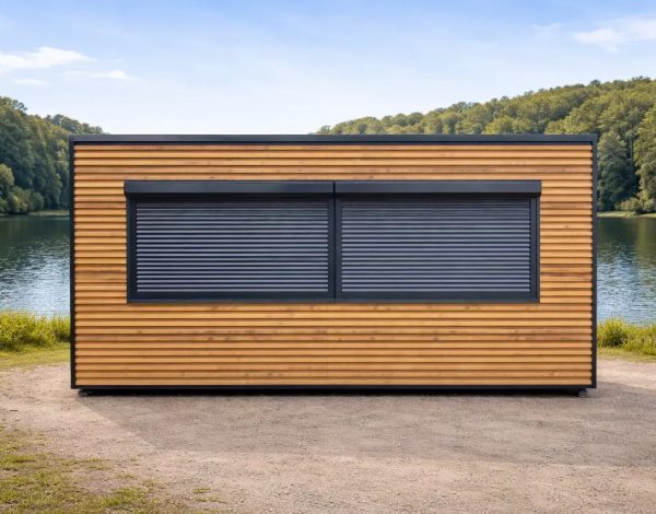 Portable catering kiosk with horizontal timber cladding and twin anthracite roller shutters, front elevation beside a lake with woodland backdrop