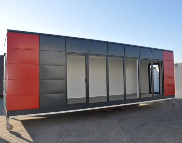 Dark anthracite and red modular portable building with full-width glazed frontage and wide sliding door panels