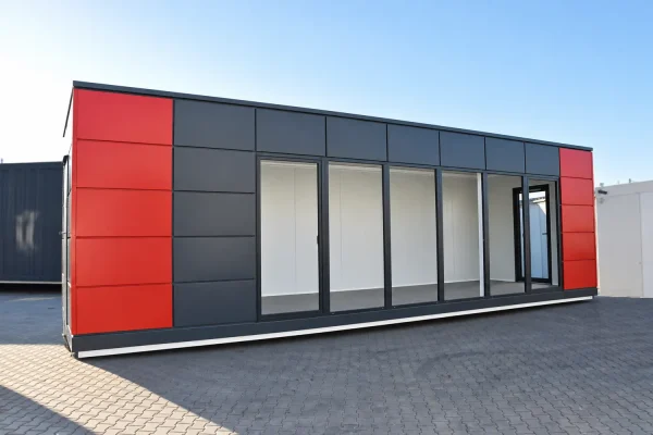 Dark anthracite and red modular portable building with full-width glazed frontage and sliding door panels side view