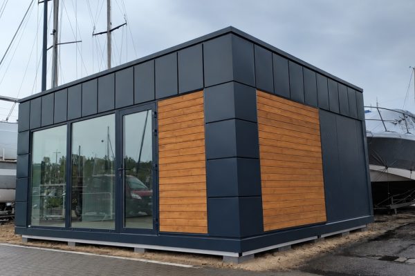 Exterior of the Tracy modular building with dark cladding, timber feature panels and large glazed frontage