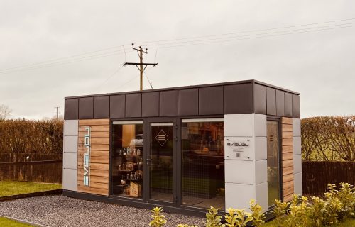 Modular retail pod with timber and white panel cladding, glazed double doors and dark fascia used as a shop