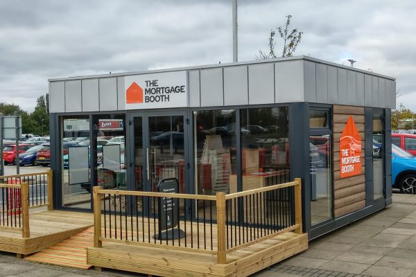 Modular office pod The Mortgage Booth grey and timber cladding glazed sides with decked ramp in car park