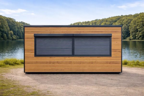 Portable catering kiosk with horizontal timber cladding and twin anthracite roller shutters, front elevation beside a lake with woodland backdrop