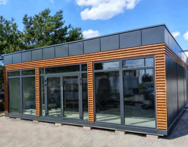 Modular portable building with natural timber cladding wide glazed frontage and grey metal roof band