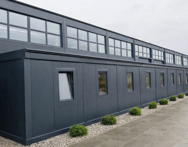 Dark anthracite modular office building with full-width clerestory glazing and small side windows